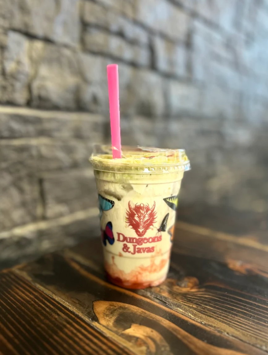 Cup with a pink straw on a wooden surface against a stone wall background