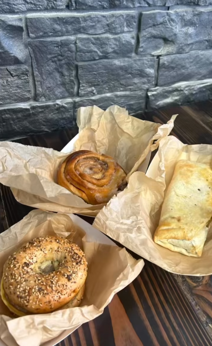 Three pastries in paper wrappings on a stone surface